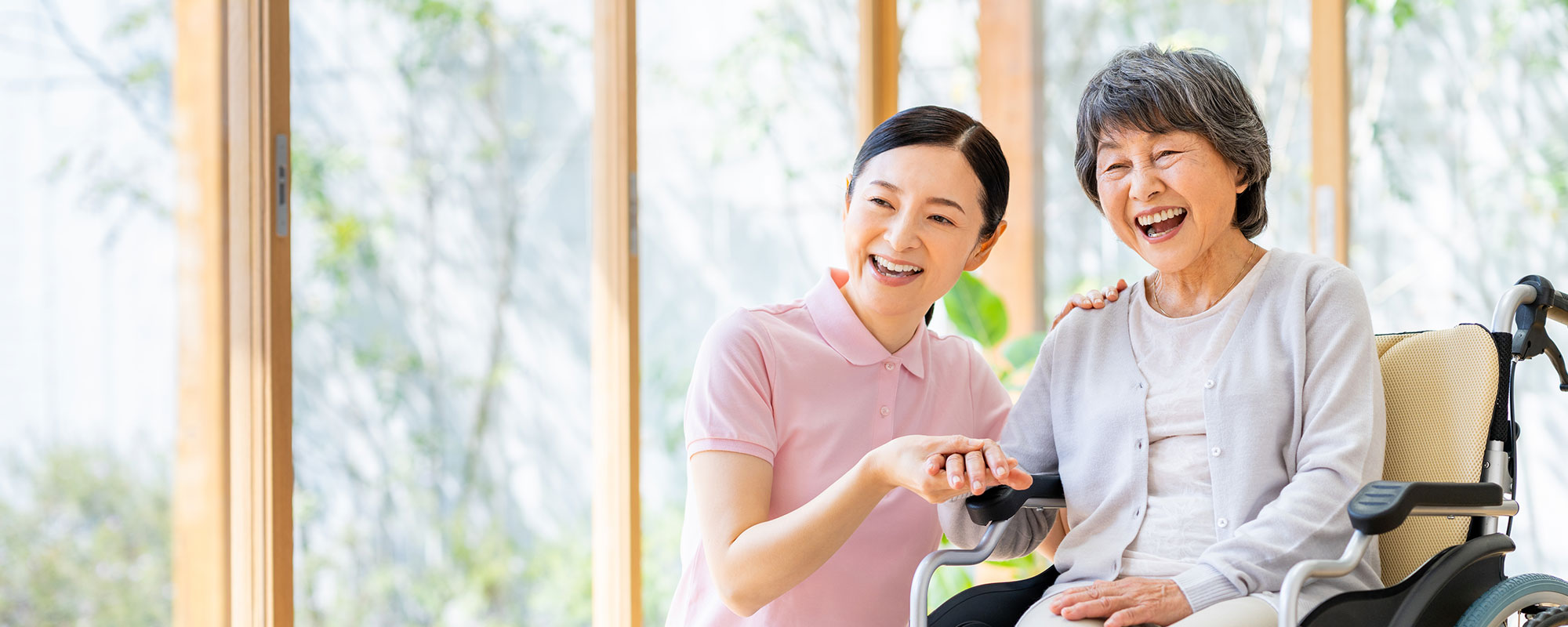 介護職員と高齢入居者がタブレットを一緒に操作し、笑顔で交流している場面